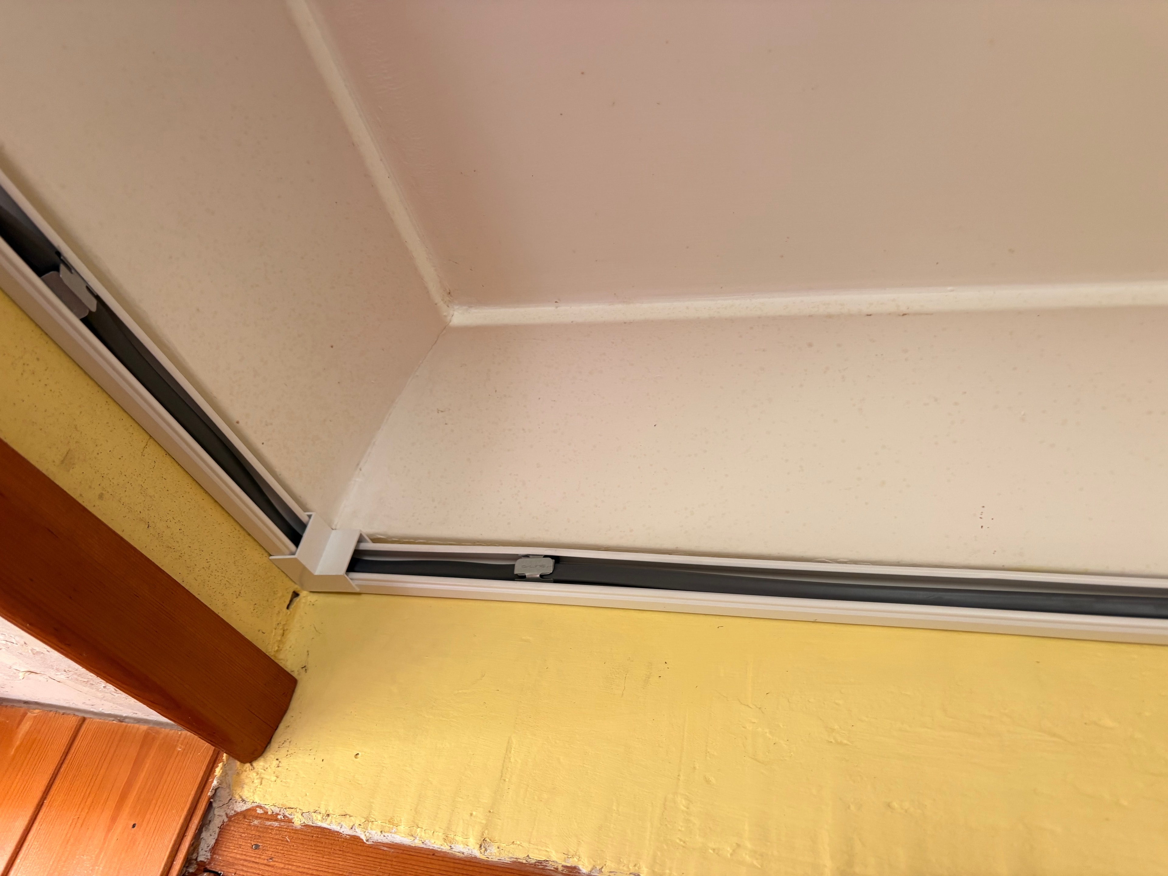 Surface trunking installed at ceiling and wall junction — clean corner detail on the Goodmayes storage heater installation