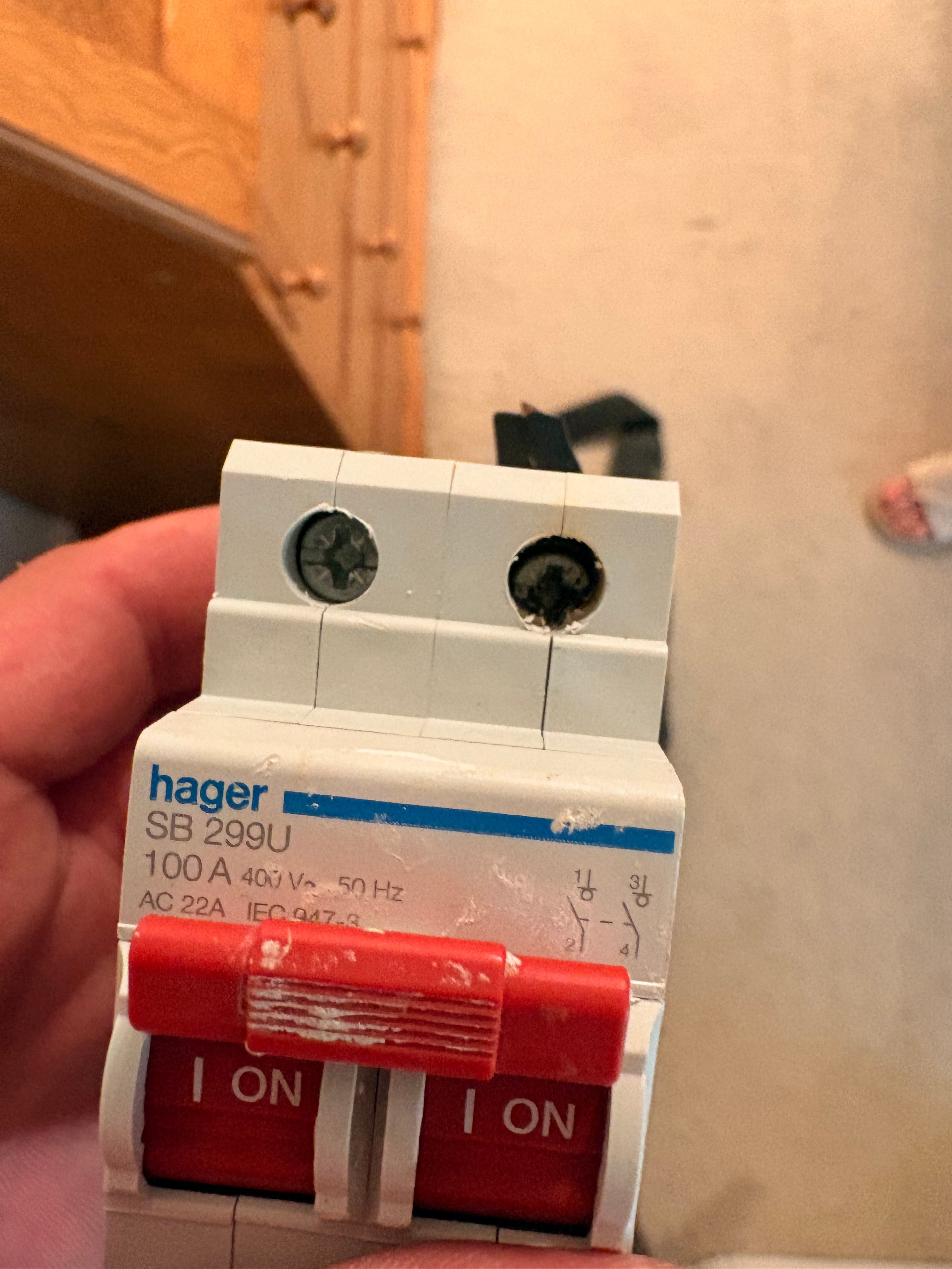 Rear view of the faulty Hager main switch showing heat discolouration and damage to the terminal block — emergency replacement in Weybridge
