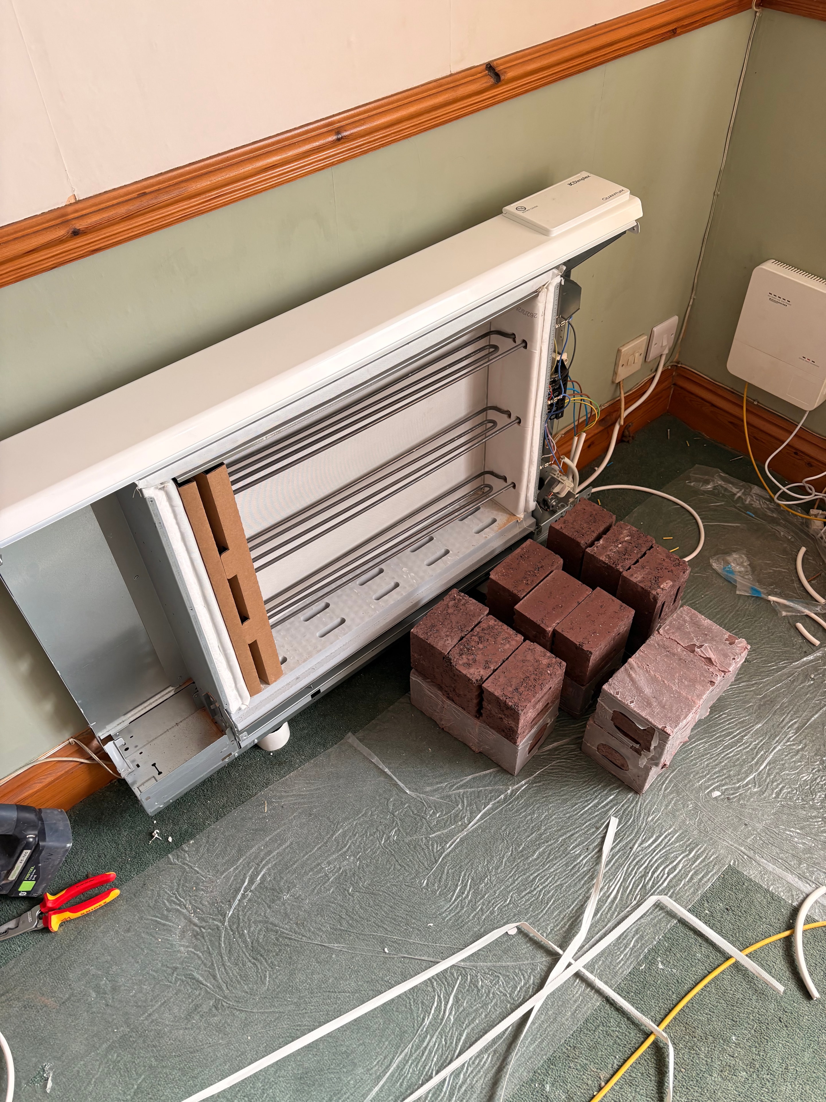 Storage heater open mid-installation showing internal heating elements and brickwork — Goodmayes government grant job